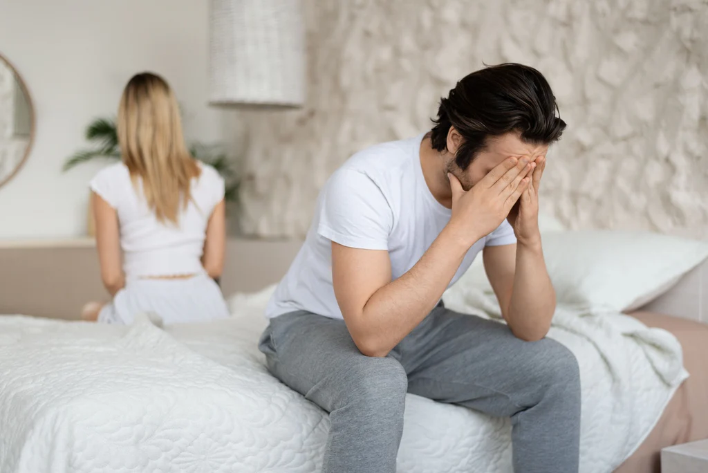 Man looking thoughtful in bed, experiencing low libido due to stress and lifestyle factors